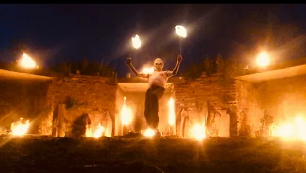 Fire performance at ruins, arms raised with flaming torches